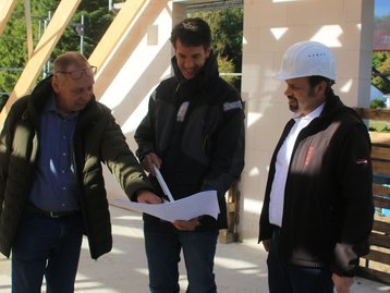 Persönliche Baubesprechung vor Ort Drei Personen besprechen Baupläne auf einer Baustelle