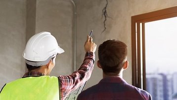Baumängel frühzeitig erkennen und prüfen Bauleiter begutachtet einen Riss an einer Rohbauwand